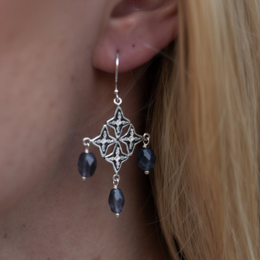 Sterling silver chandelier earrings with four linked star medallions and three faceted iolite nugget drops, on model Windsor Collection 2009, Lori Bonn Archive.