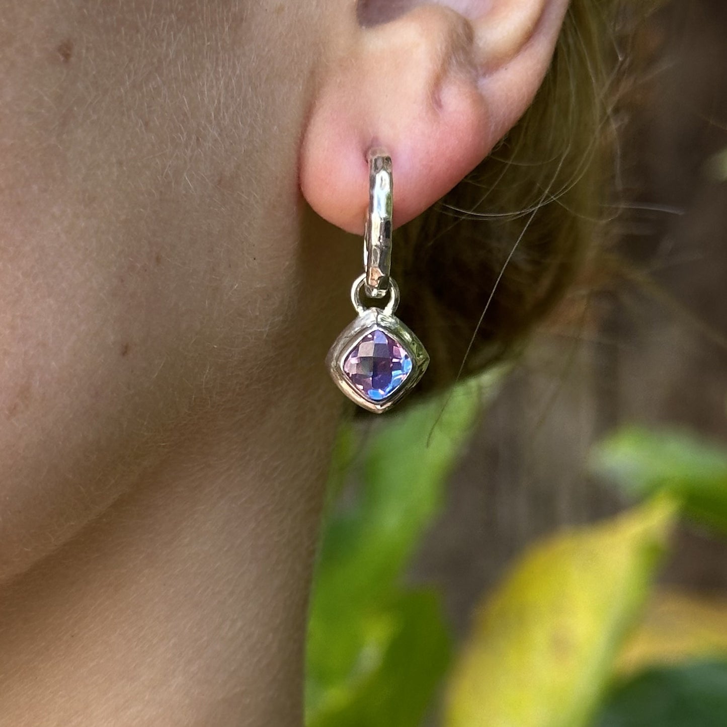 Sterling silver hand-hammered swirl hoop earring with cushion-cut rainbow lavender quartz charm drop, straight-on view, worn, Lori Bonn Splash Collection 2009 Archive sample.