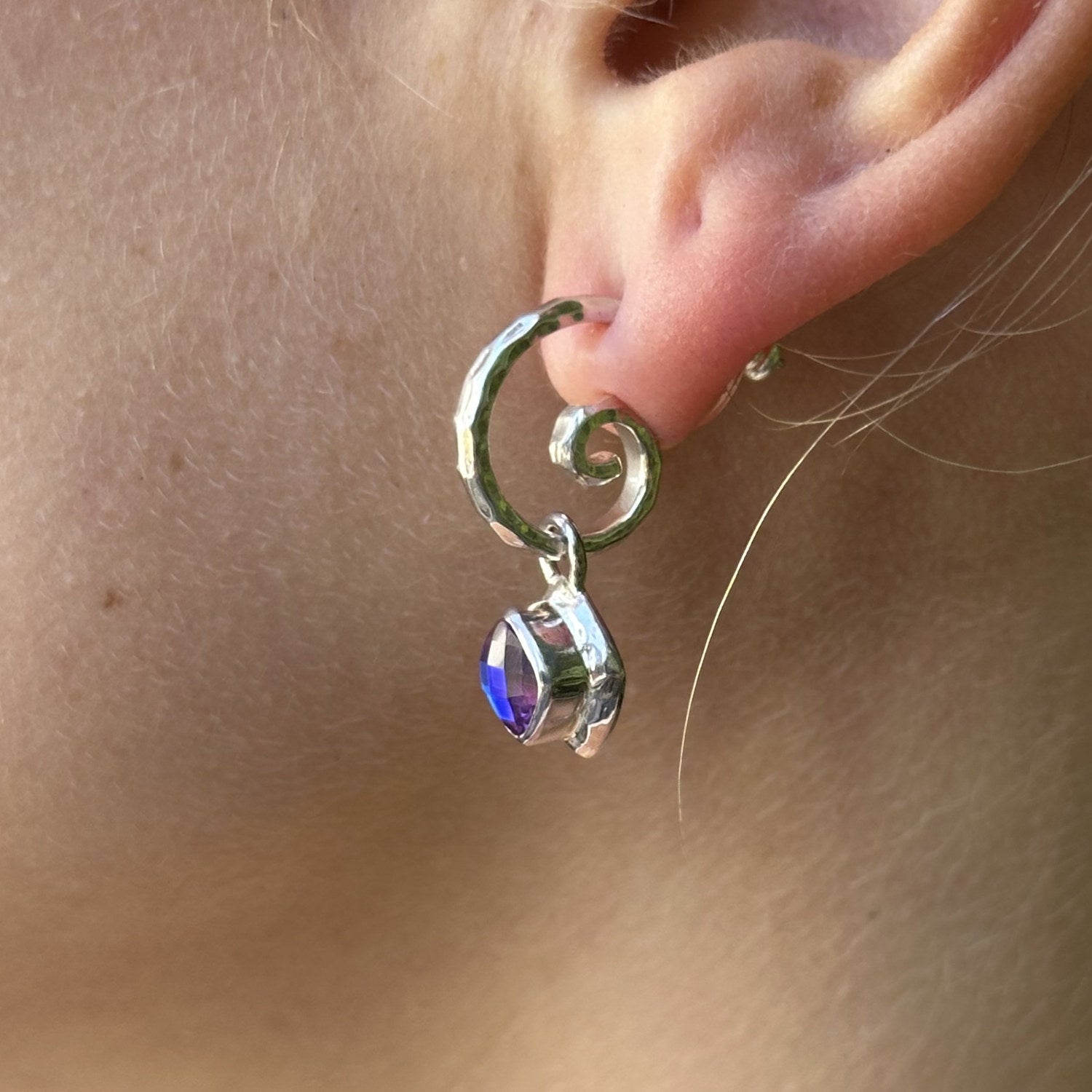 Sterling silver hand-hammered swirl hoop earring with removable cushion-cut rainbow lavender quartz charm drop, worn, Lori Bonn Splash Collection 2009 Archive sample.