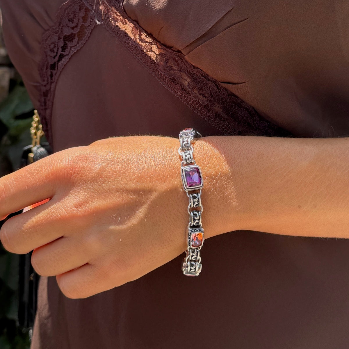 Sterling silver link bracelet with cushion-cut raspberry topaz and twilight topaz in twisted rope and granulation bezels, scroll openwork links, and toggle clasp on model wrist. Parisian Muse Collection, 2004, Lori Bonn Archive.