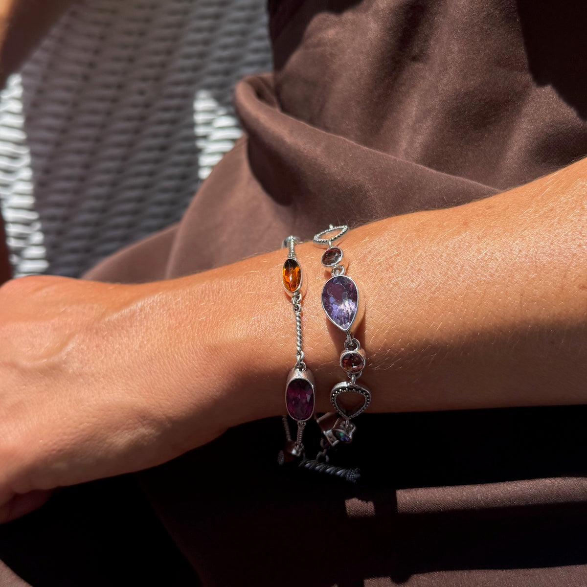 Close-up of a wrist wearing two silver bracelets with gemstones.