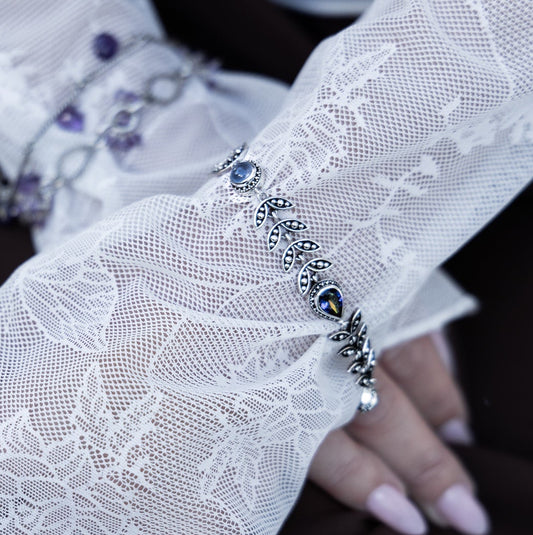 Sterling silver leaf vine link bracelet with pear-shaped mystic fire topaz and round chalcedony cabochons, toggle clasp, on model. Heirloom Collection 2002, Lori Bonn Archive.